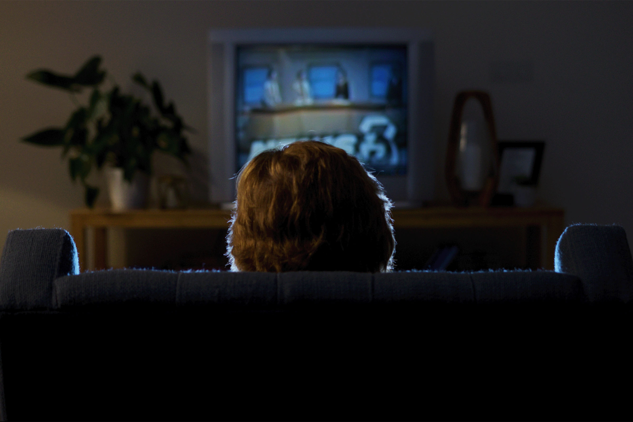 A woman watches the news on an old television set
